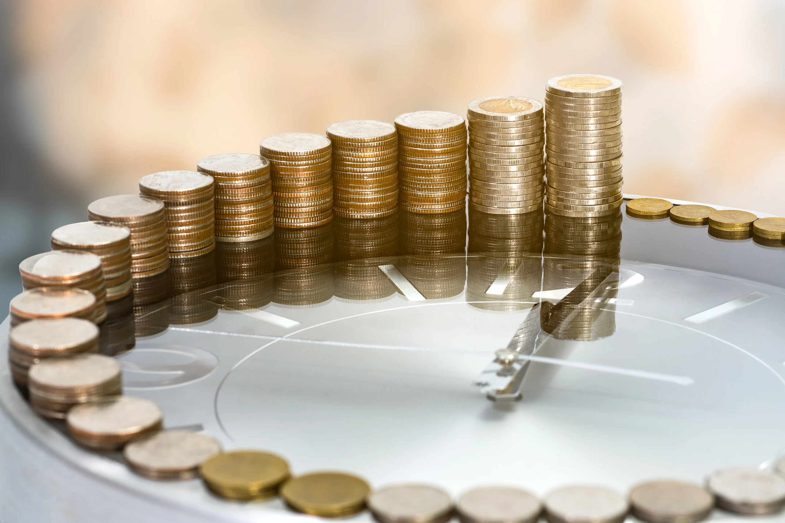 AdobeStock_283640727 coins stacks growing in size around the perimeter of a clock
