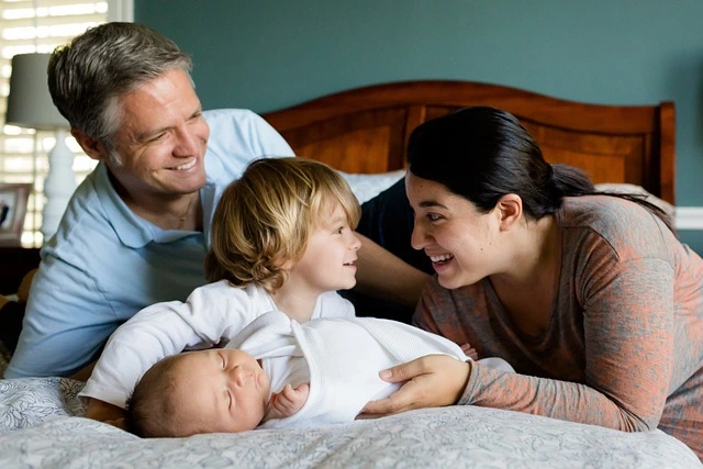 Life Insurance Family of four playing and smiling on a bed.
